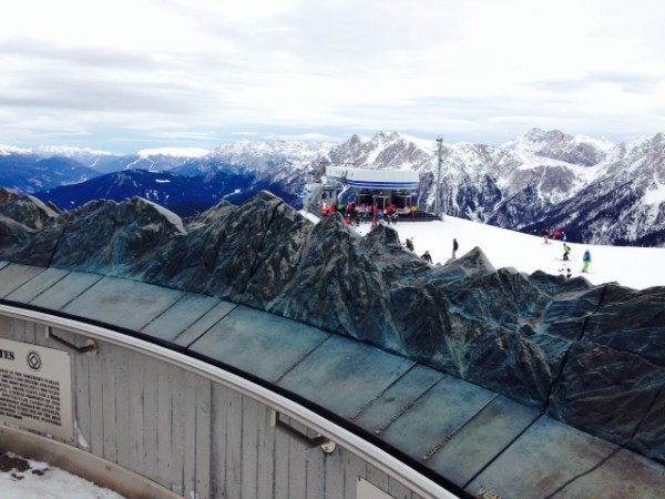 Kronplatz , scultura in bronzo della catena montusoa sullo sfondo